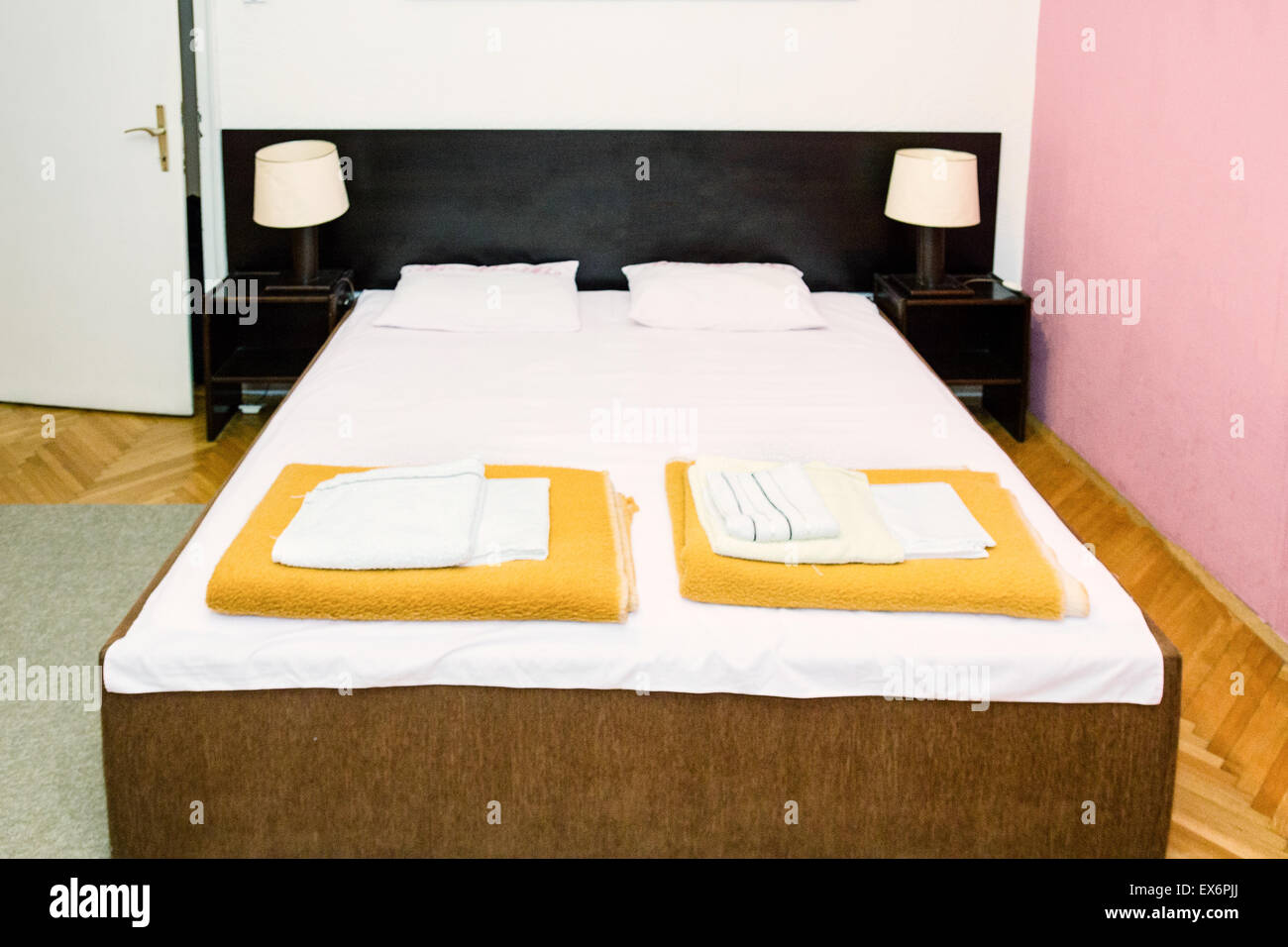 Retro bedroom interior. Double bed in vintage indoor room. Bed with clean white sheets and passed down two yellow blankets with  Stock Photo