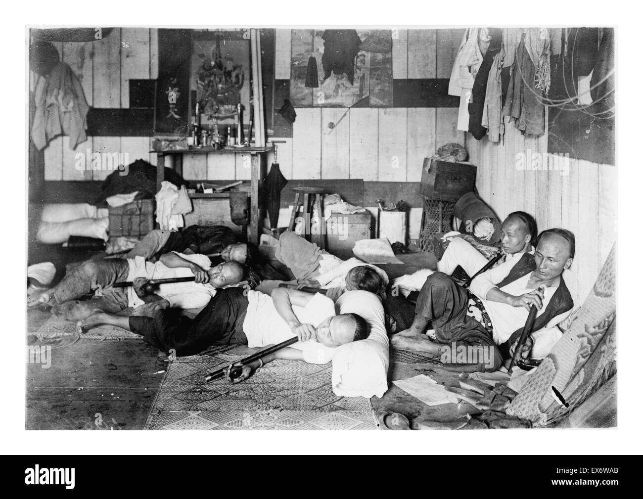Opium den on Malinta Street, Manila, Philippine Islands. Photo shows an interior view of an opium den with several men reclining, smoking long opium pipes. . 1924. Stock Photo