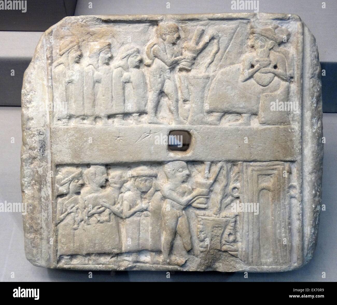 limestone plaque; Early Dynastic III. Iraq, south 2500BC. Square stone plaque with holes through the centre carved in relief. southern Mesopotamia (2900-2300 BC). They were probably dedicated in a temple and fixed to the mud-brick wall of a shrine Stock Photo