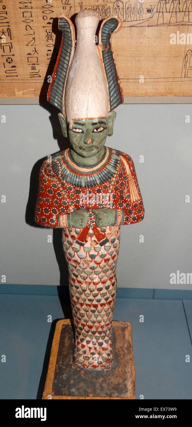 Painted wooden statue of Osiris 20th Dynasty, about 1170 BC From Thebes, Egypt. depicts the god wearing characteristic feathered crown and grasping the royal crook and flail sceptres. The green colouring of the skin reflects the god's associations with ve Stock Photo