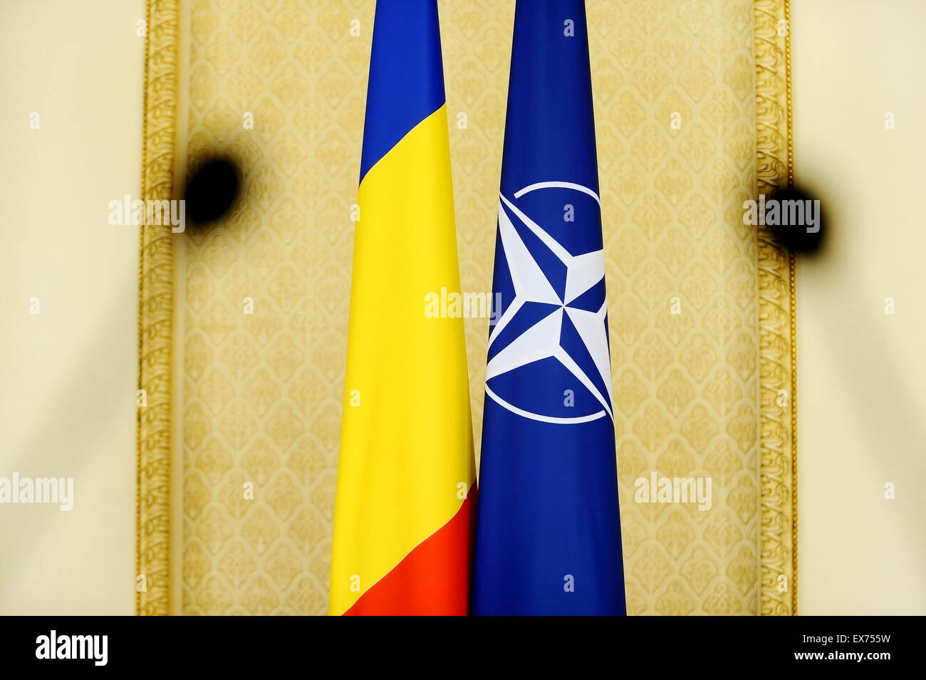 Romania and NATO flags shoot through two press microphones Stock Photo
