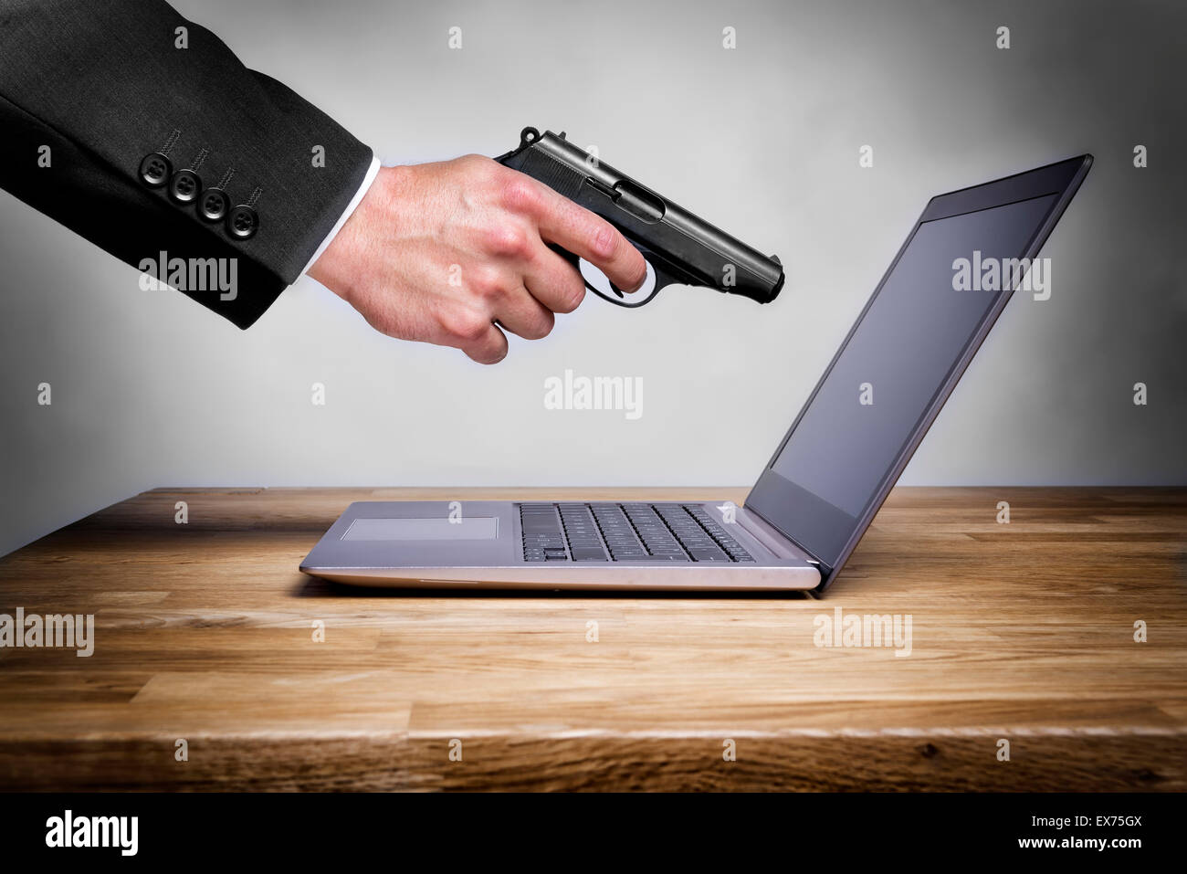 Businessman shoots with gun at his laptop Stock Photo