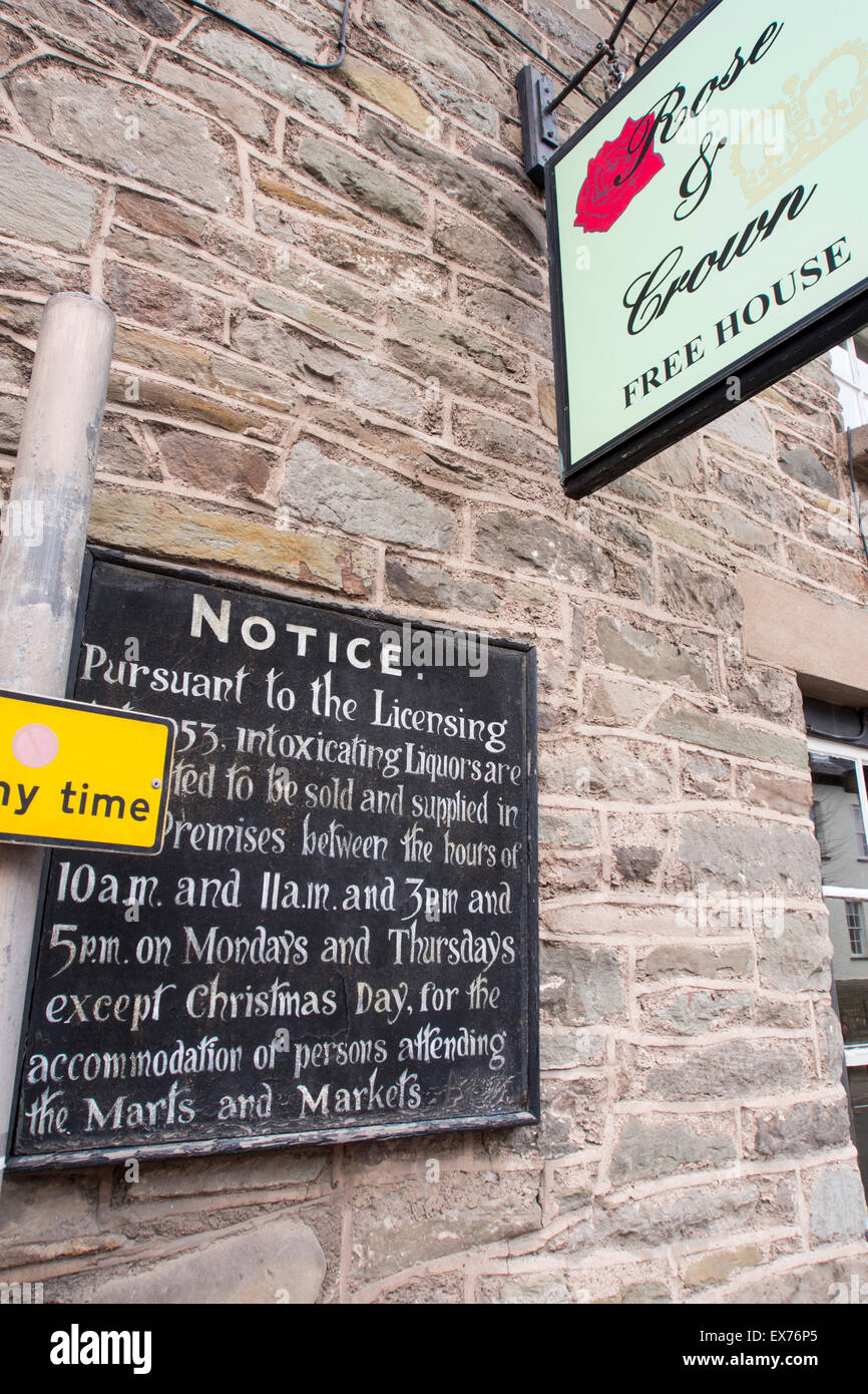 An old licensing opening hours sign on a pub in Hay on Wye, Powys