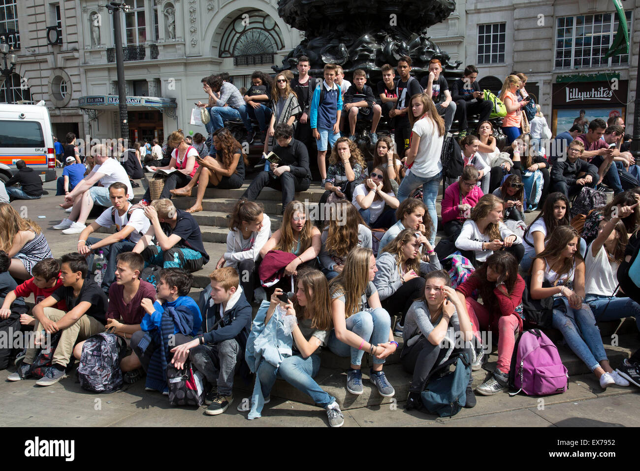 Summertime in London, England, UK. Student tourists gather en masse at the base of Eros in Piccadilly Circus. Stock Photo