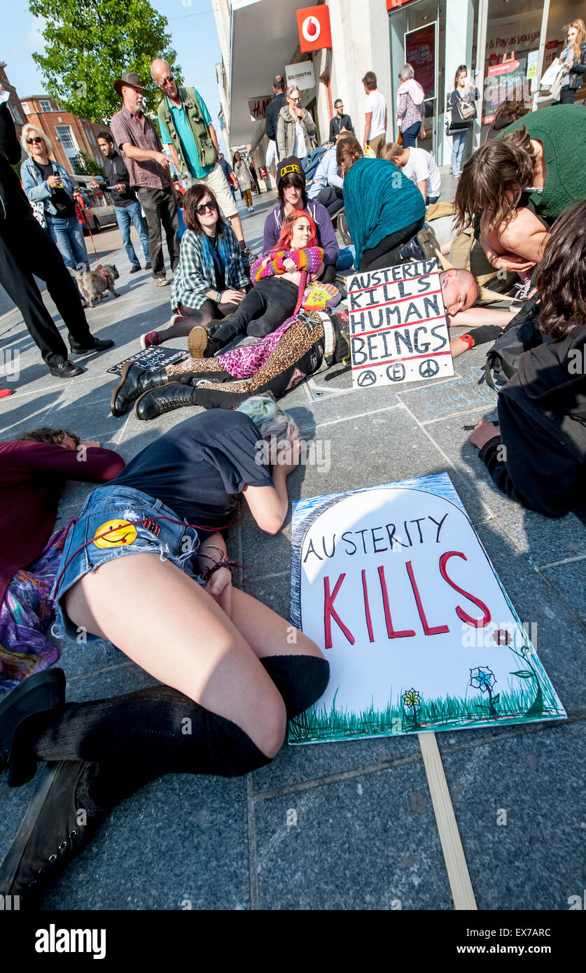 Exeter, Devon, UK. 8th July, 2015. A young woman lays beside an Austerity Kils placard during the Exeter Budget Day Action #AusterityKills in Exeter City Centre on july 8th, 2015 in Bedford Square, Exeter, UK Credit:  Clive Chilvers/Alamy Live News Stock Photo