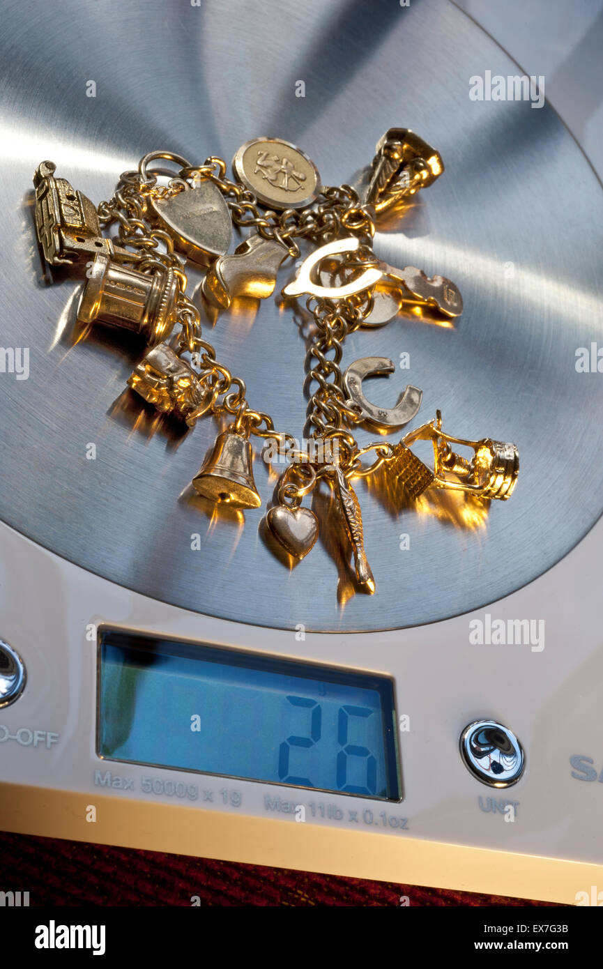 GOLD SCRAP WEIGHT WEIGHING SELLING SALE SELL old charm bracelet on digital weighing machine displaying 26 grams in weight Stock Photo