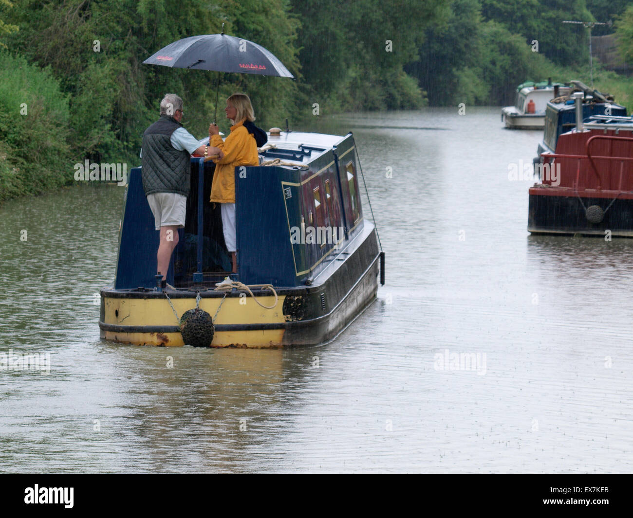 Helming a canal boat in the rain under an umbrella, Kennet ...