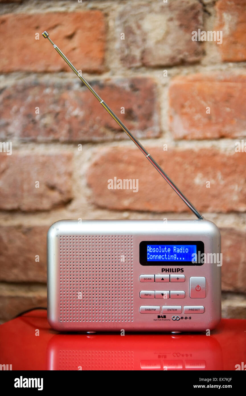 Small silver digital radio tuned to Absolute Radio on a red table against a  rustic interior brick wall Stock Photo - Alamy