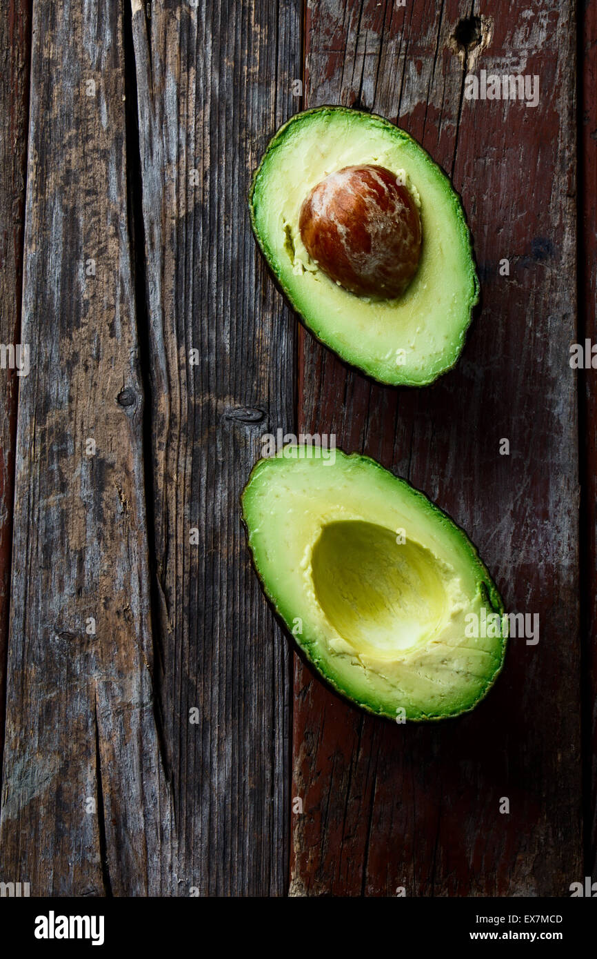 Halved avocados on rustic wooden background. Top view Stock Photo - Alamy