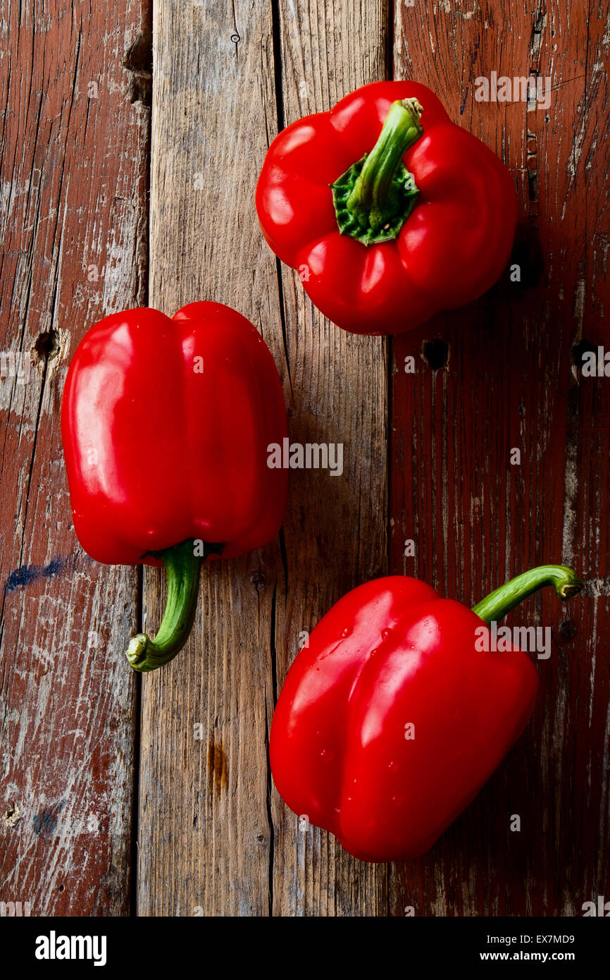 Top view of Ttree red bell peppers on old wooden planks. Rustic take. Stock Photo
