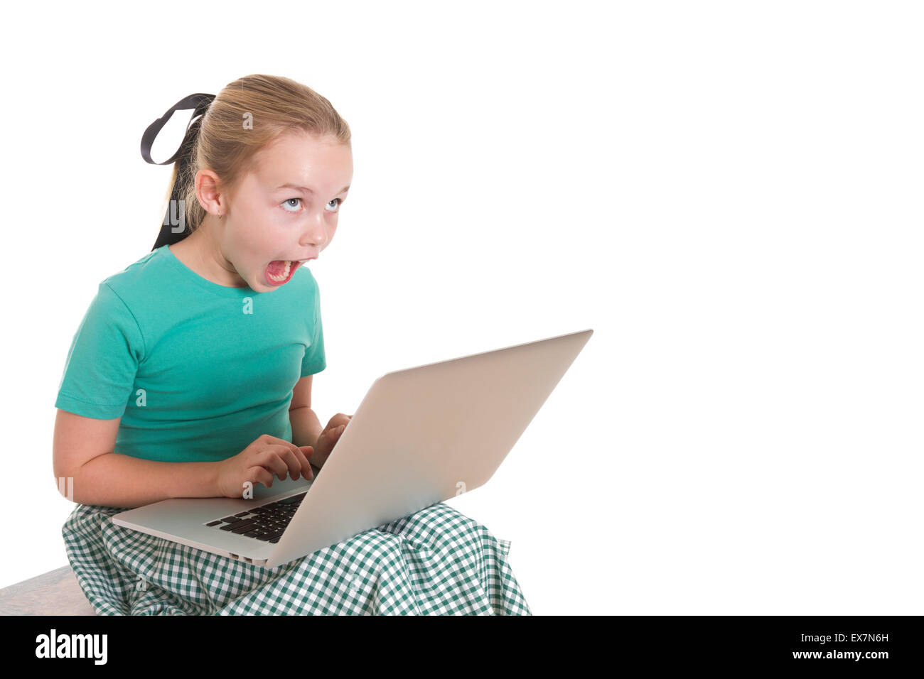 Young girl with a computer on her lap, looking totally amazed and shocked by what she is looking at. Stock Photo