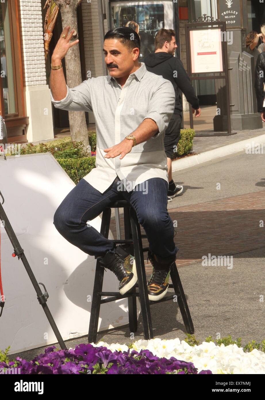 Shahs of Sunset actor, Reza Farahan sitting on a stool, does an ...