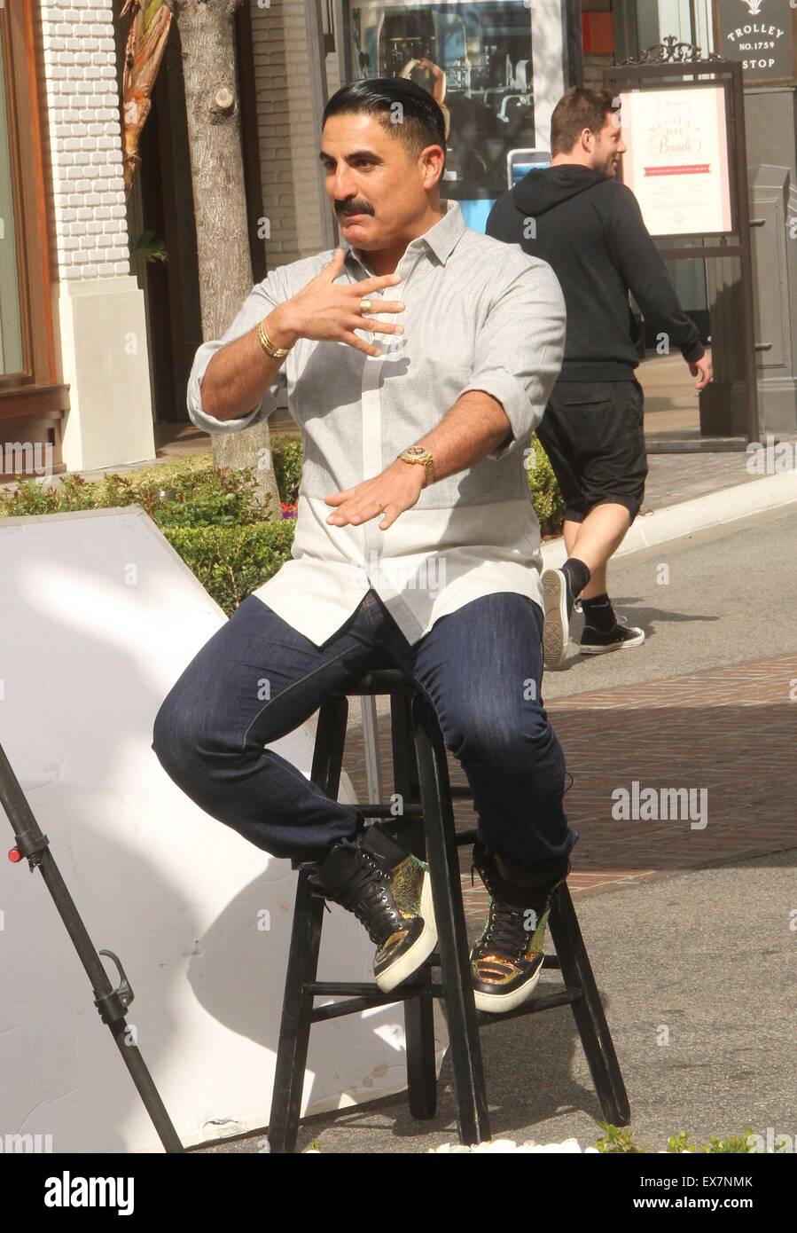 Shahs of Sunset actor, Reza Farahan sitting on a stool, does an ...
