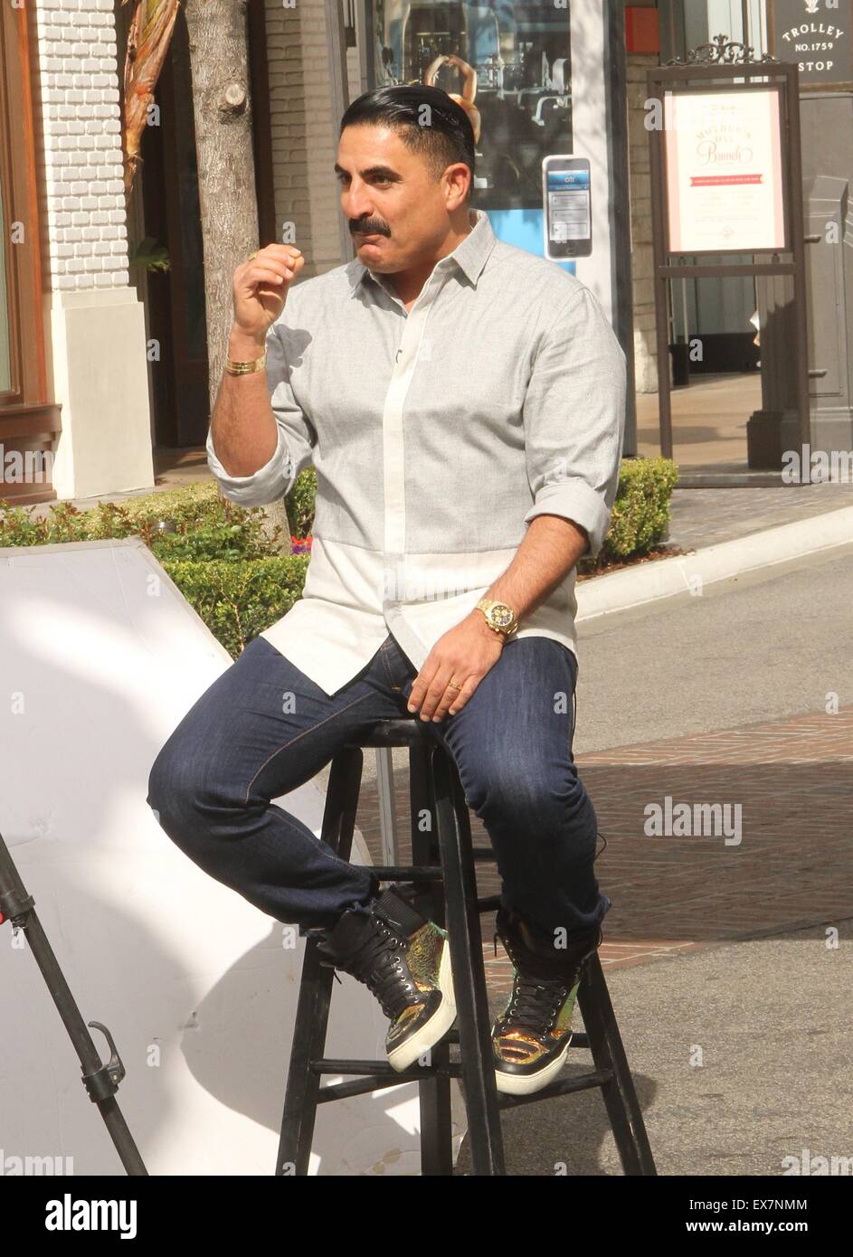 Shahs of Sunset actor, Reza Farahan sitting on a stool, does an ...