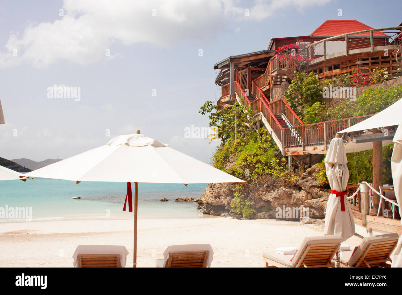 A view of St. Jean Beach, a parasol umbrella, beach chairs and the famous Eden Rock Hotel, in St. Barts Stock Photo