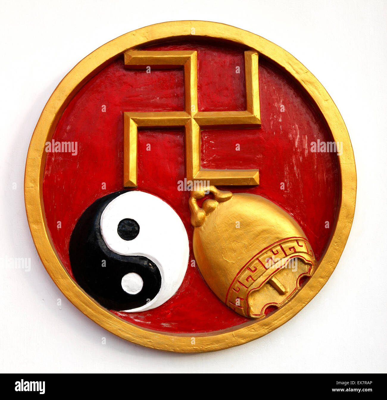 A wall decoration in Bali, with a golden swastika, a ying yang and a golden bell. This is a religious symbol of good luck. Stock Photo