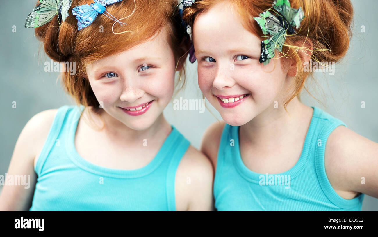 Smiling redhead twin sisters with butterfly in hair Stock Photo