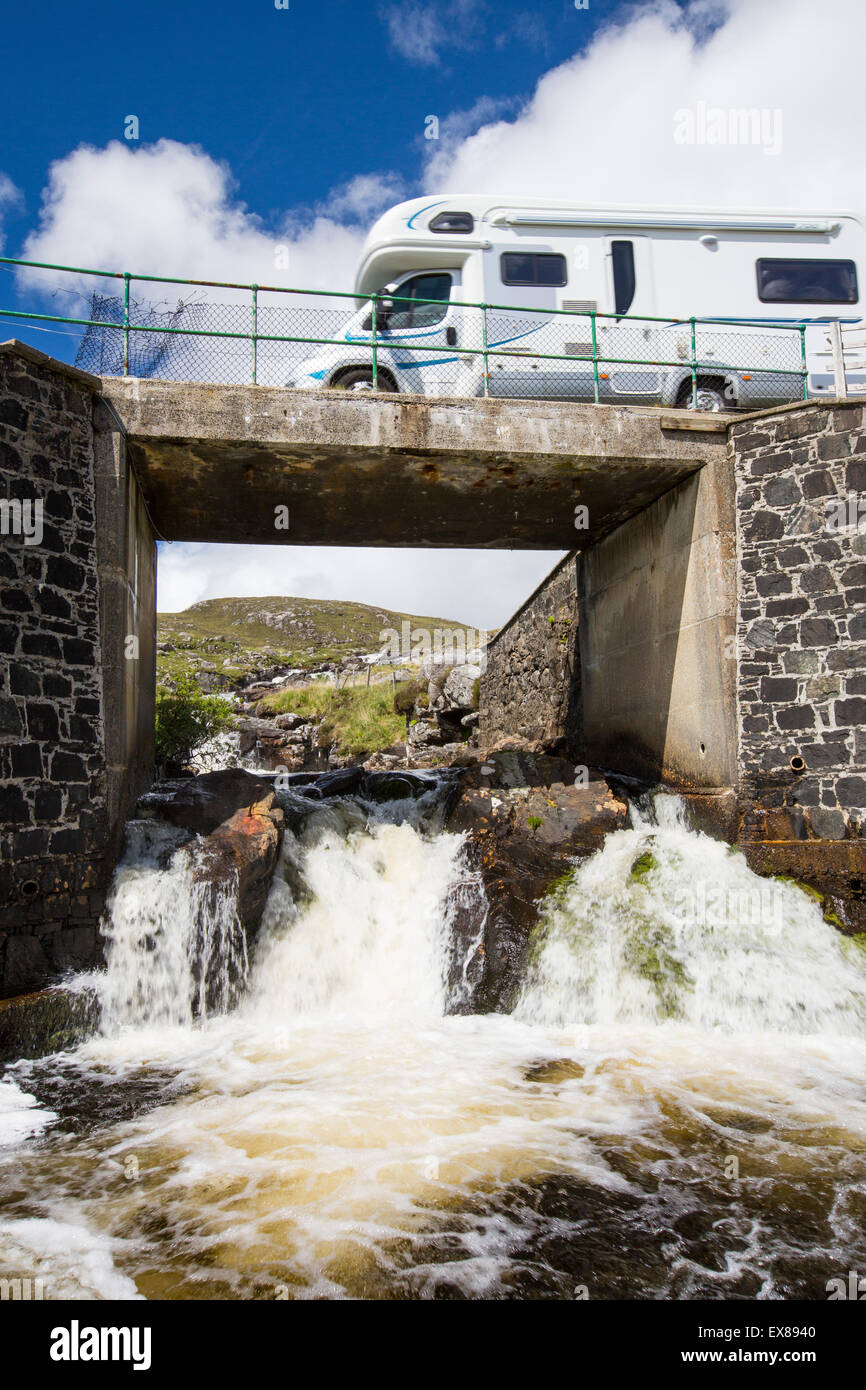 A camper van crossing a bridge over the Abhainn Eadarra amongst rugged mountain scenery on North East Harris, Outer Hebrides, Scotland, UK. Stock Photo