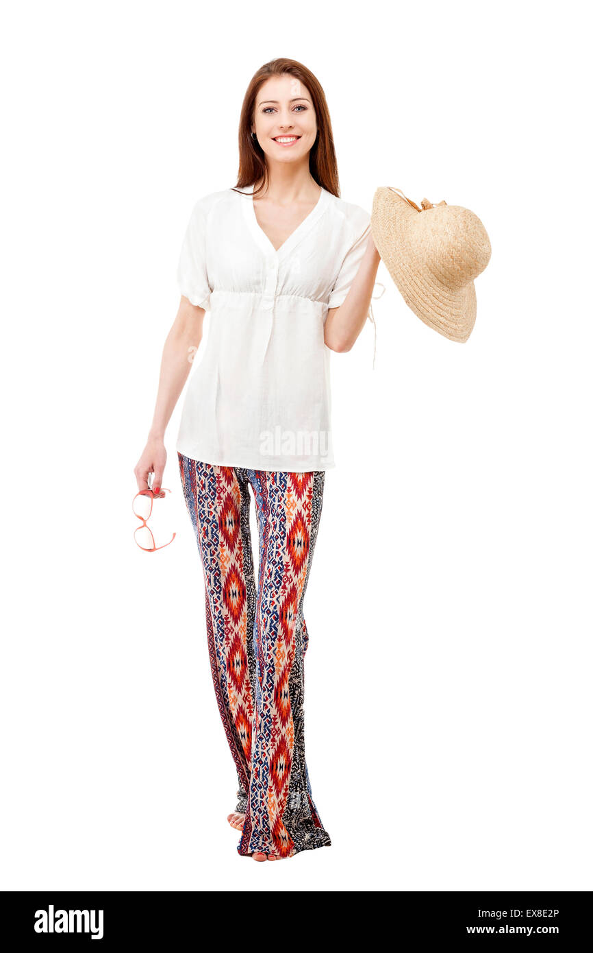 Young beautiful woman wearing hippie summer clothes with straw hat and sunglasses isolated on white. Stock Photo