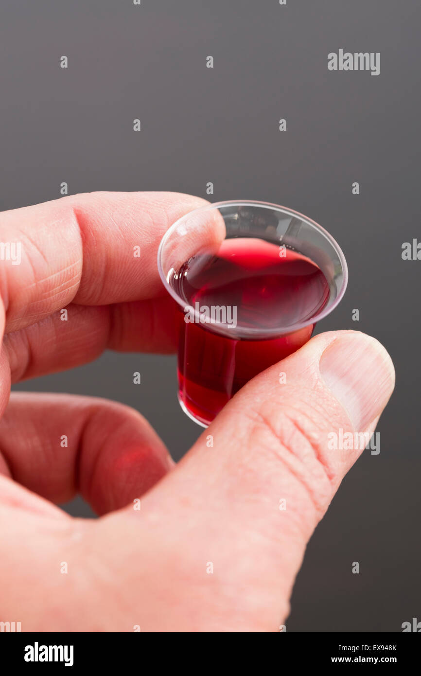 Man's hand holding small cup of mass wine Stock Photo