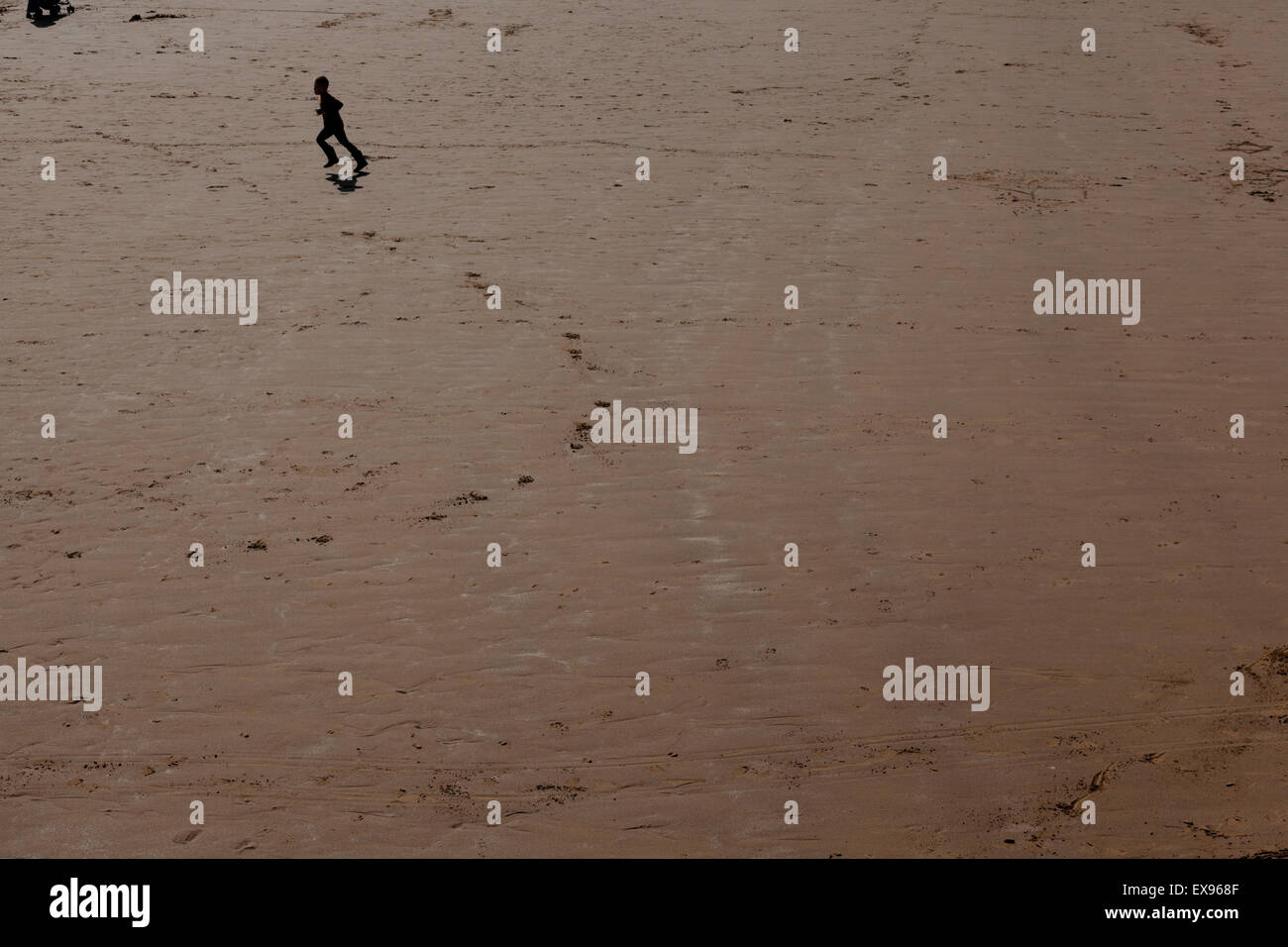 A child runs across the empty beach at Scarborough, Yorkshire Stock Photo