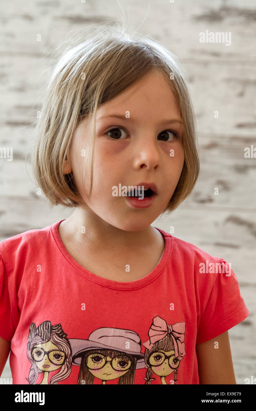 Surprised little girl in front of white wooden background ...