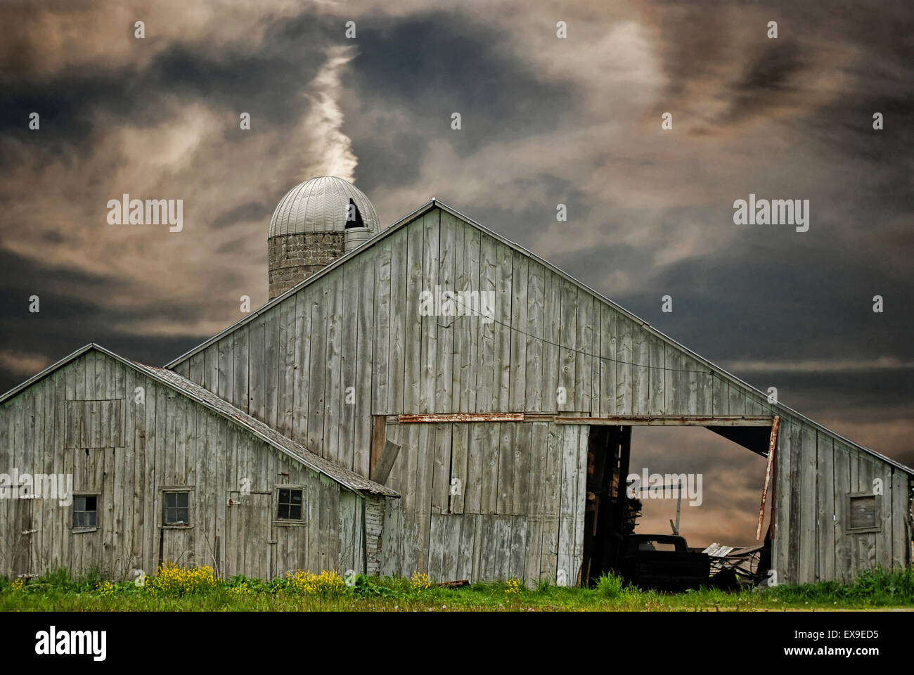 Weathered old barn and silo with sunset sky. Stock Photo