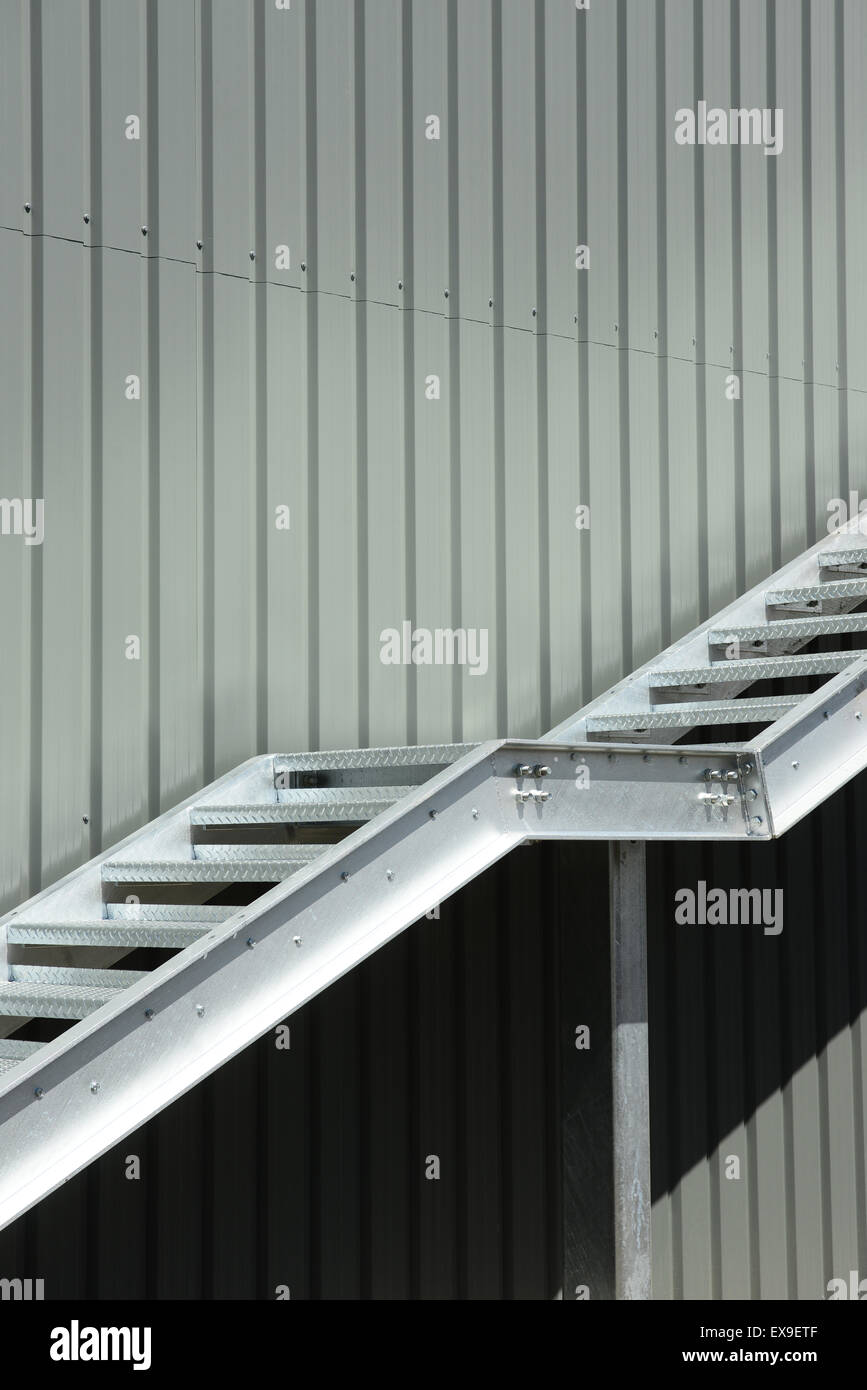 Metal staircase rising up the outside of a steel clad warehouse Stock Photo