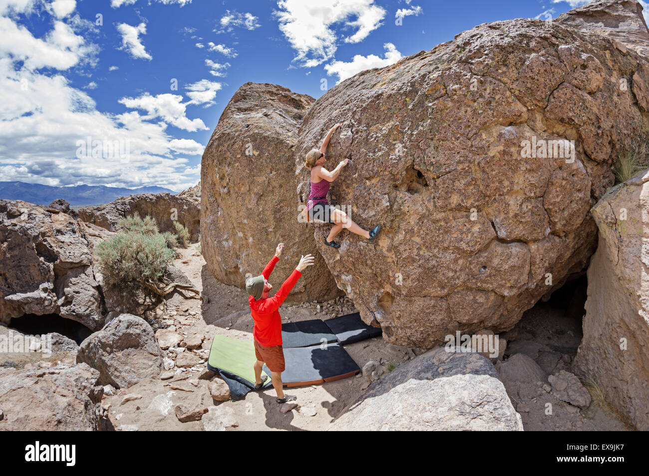 a couple bouldering at the Happy Boulders with the woman climbing and the man spotting Stock Photo