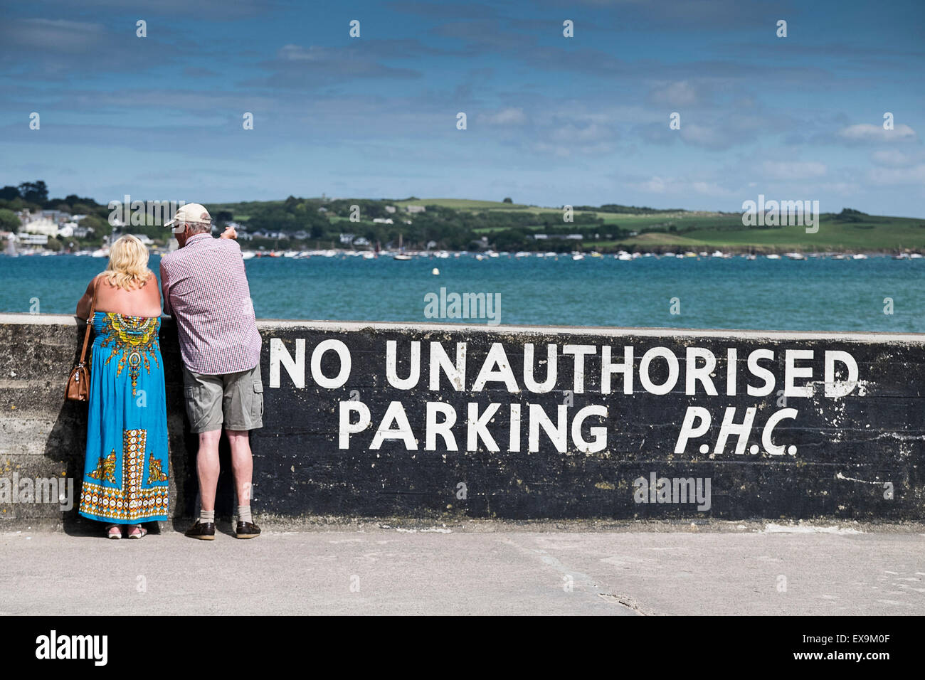 Two holidaymakers standing on the quay in Padstow and overlooking the camel Estuary in Cornwall. Stock Photo