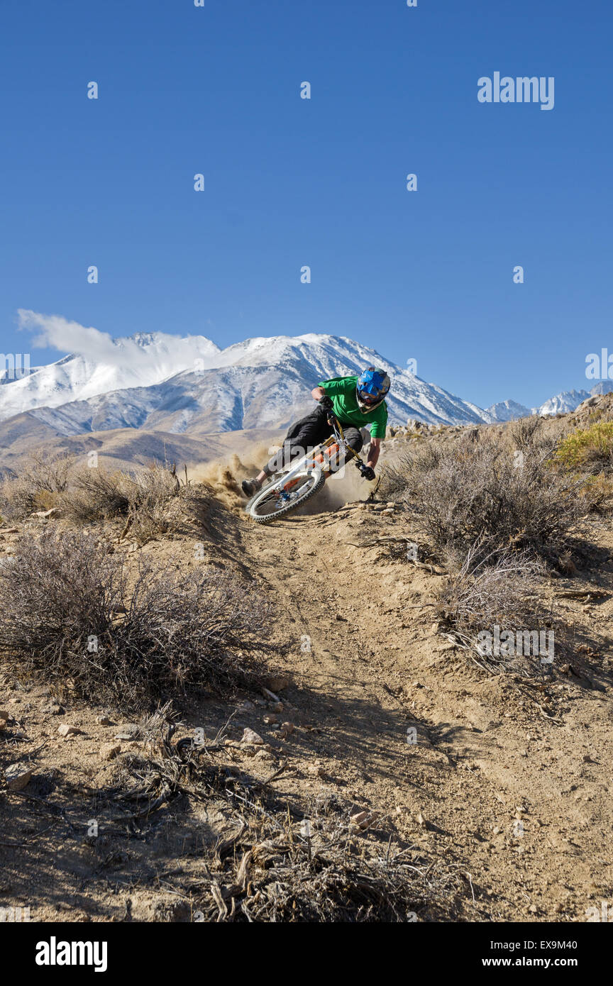 a mountain biker leans into a turn in the desert foothills with mountain in the background and copy space Stock Photo