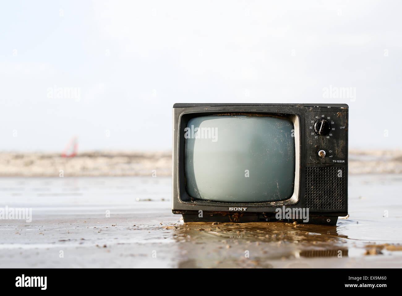 An old TV, washed up out of the sea onto an English sandy shoreline. Environmentally damaging to the beach at weston super mare, UK Stock Photo