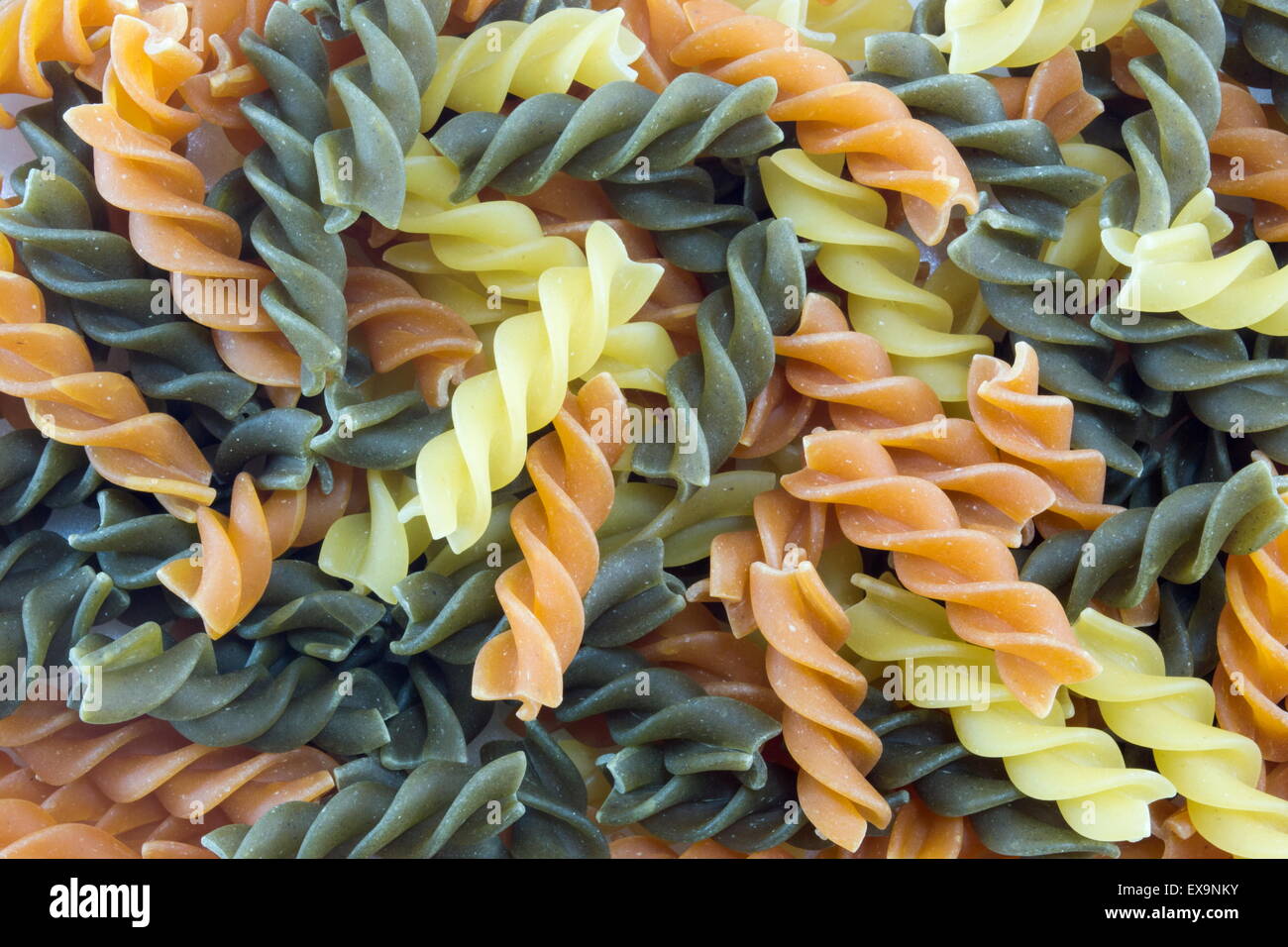 Tri-Color unprepared macaroni pasta stacked to form background Stock Photo