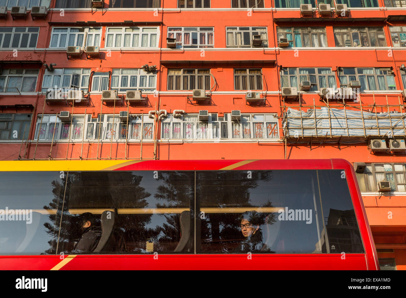China, Hong Kong, Young man peers from bus window beneath high rise apartment building on Canton Road on Kowloon Peninsula Stock Photo