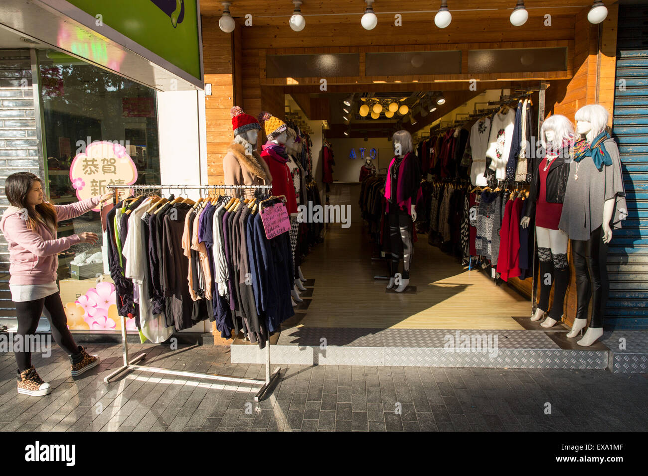 China, Hong Kong, Young woman sets out women’s clothes on sidewalk