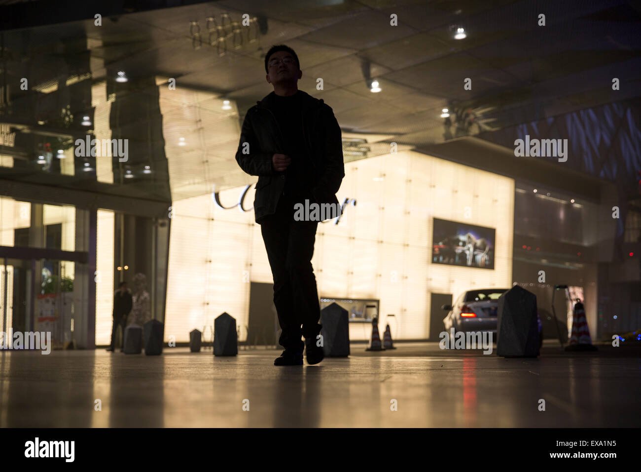 China, Shanghai, Young man walks past Cartier store at IFC Shopping Mall at night on winter evening Stock Photo