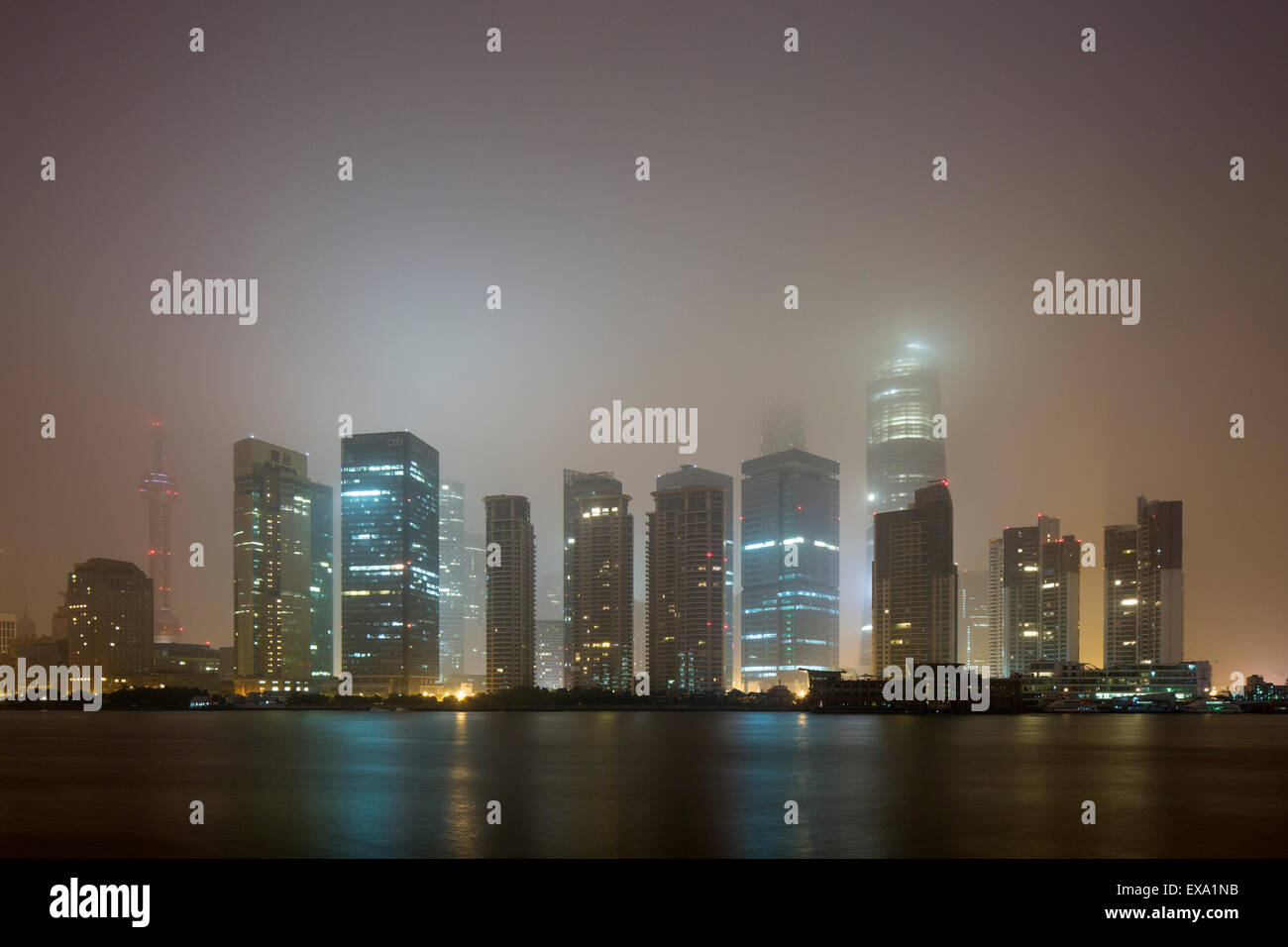 China, Shanghai, Skyscrapers in skyline of Pudong District lost in low clouds along Huangpu River on winter morning Stock Photo