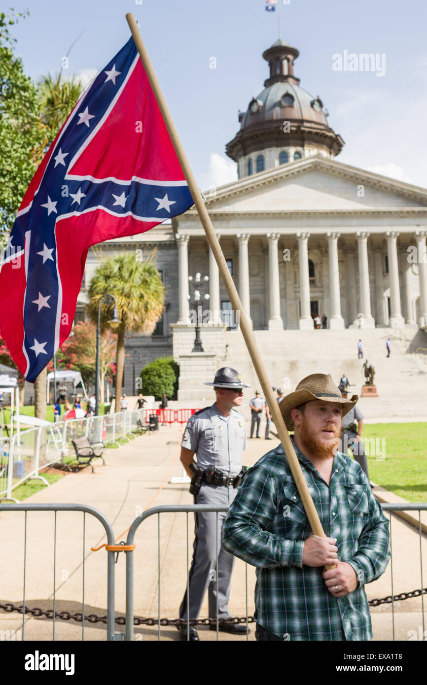 Columbia, South Carolina, USA. 09th July, 2015. The Confederate flag is held aloft by a protester outside the South Carolina State House as Governor Nikki Haley signs into law a bill to remove the Confederate flag from the capitol July 9, 2015 in Columbia, SC. The movement to remove the symbol of white supremacy gained momentum after the shooting of nine black people in Charleston last month. Stock Photo