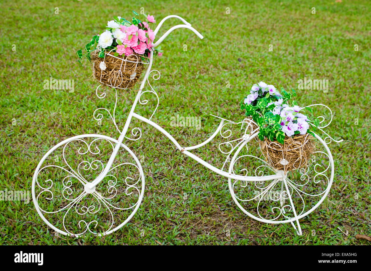 White steel bike and flower pots on the grass Stock Photo