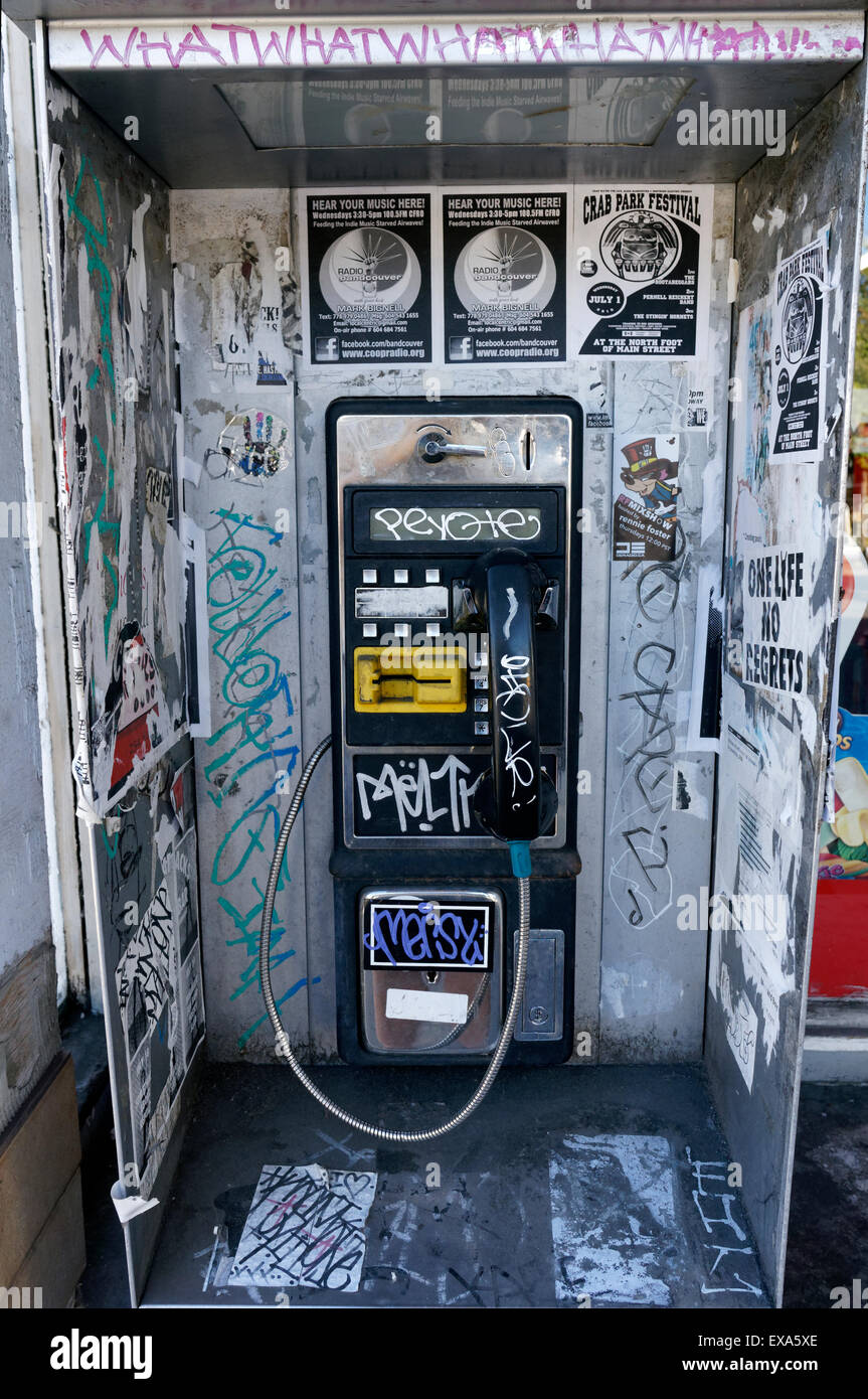 Old coin-operated payphone covered in graffiti, Vancouver, BC, Canada Stock Photo