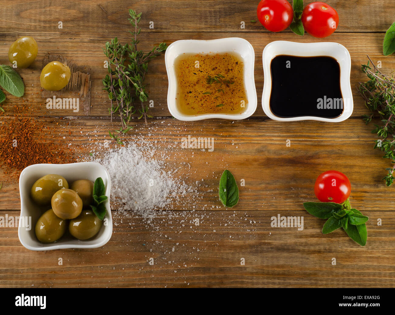 Dressing ingredients on a rustic wooden background. Olive oil, balsamic vinegar, herbs, salt and pepper. Top view Stock Photo