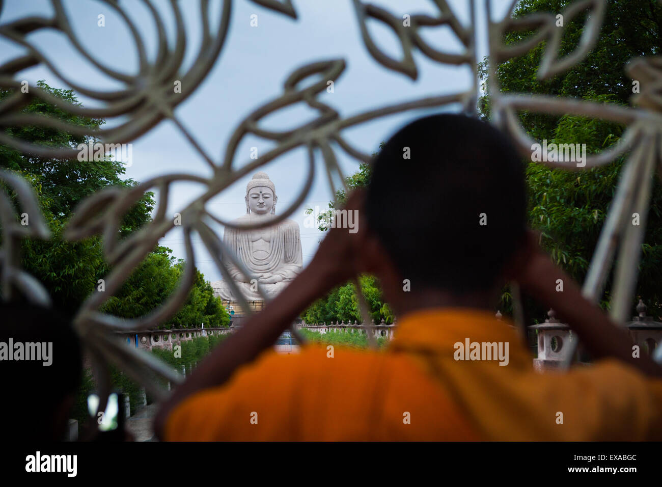 A monk is looking at a 64-feet-high Great Buddha statue from behind the fence in Bodh Gaya, Bihar, India. Stock Photo