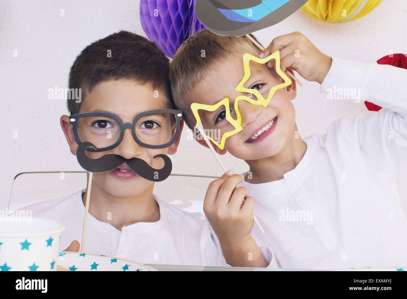 Boys wearing funny disguises at birthday party Stock Photo