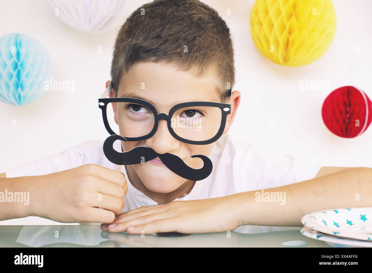 Boy wearing fake glasses and mustache at a birthday party, portrait Stock Photo