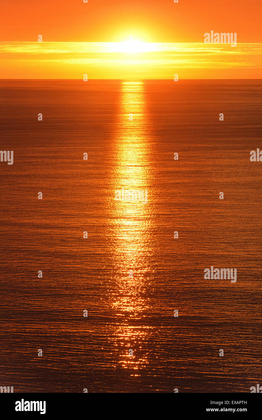 Sunrise scenery at the ocean, with the sun reflected on the gold water Stock Photo