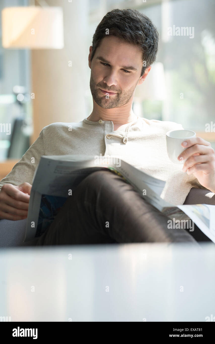 Man reading newspaper and drinking coffee Stock Photo
