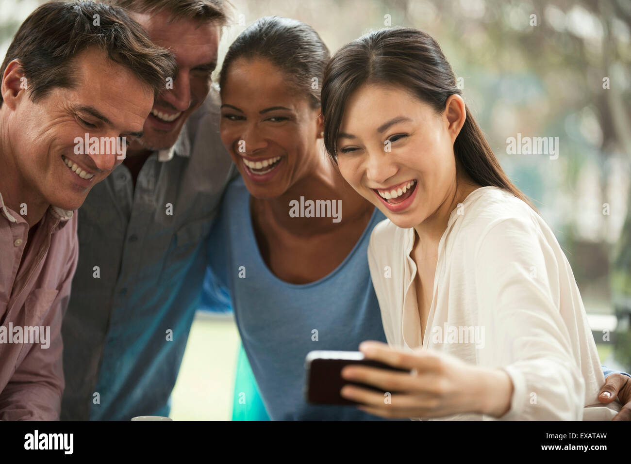 Friends posing for smartphone selfie, laughing cheerfully Stock Photo