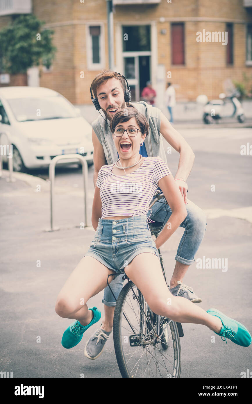 couple of friends young man and woman riding bike in the city Stock