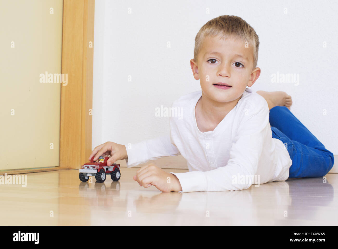 Boy lying on floor playing with toy truck Stock Photo