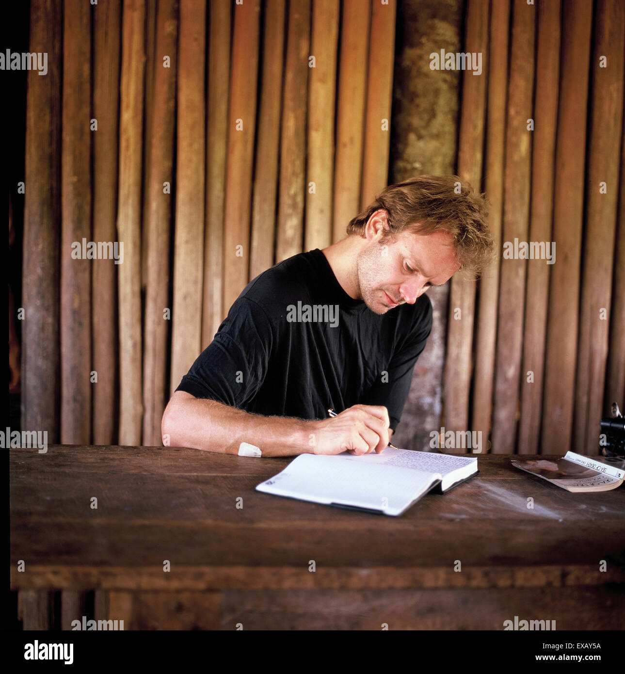 Pavuru village, Brazil. Sting writing at a table in an Indian house; Xingu Indigenous area, Brazil; Nov 1990. Stock Photo